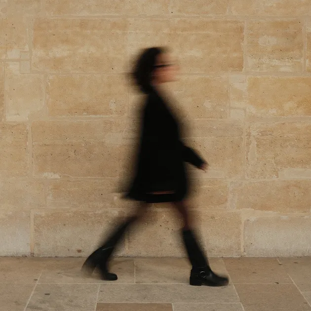 Flavie Blanchet marchant devant un mur de pierre, saisie en flou de mouvement