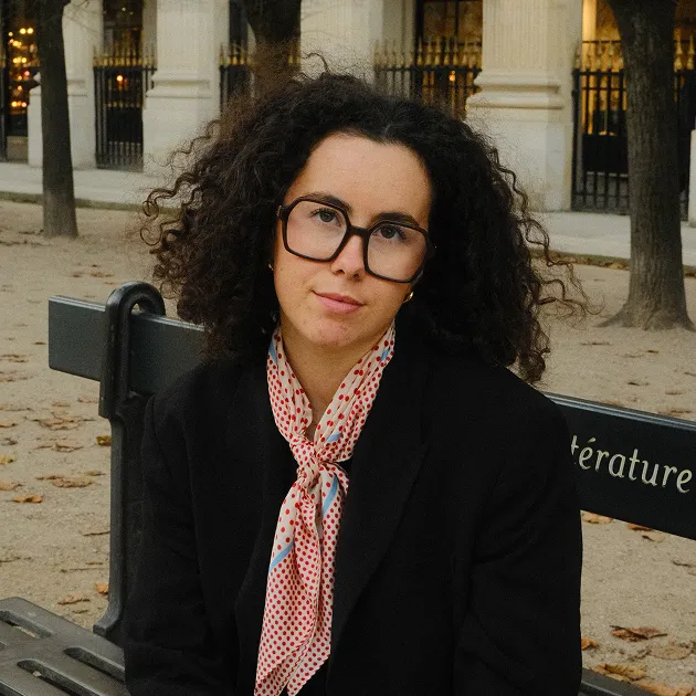 Portrait de Flavie Blanchet assise sur un banc dans un jardin parisien